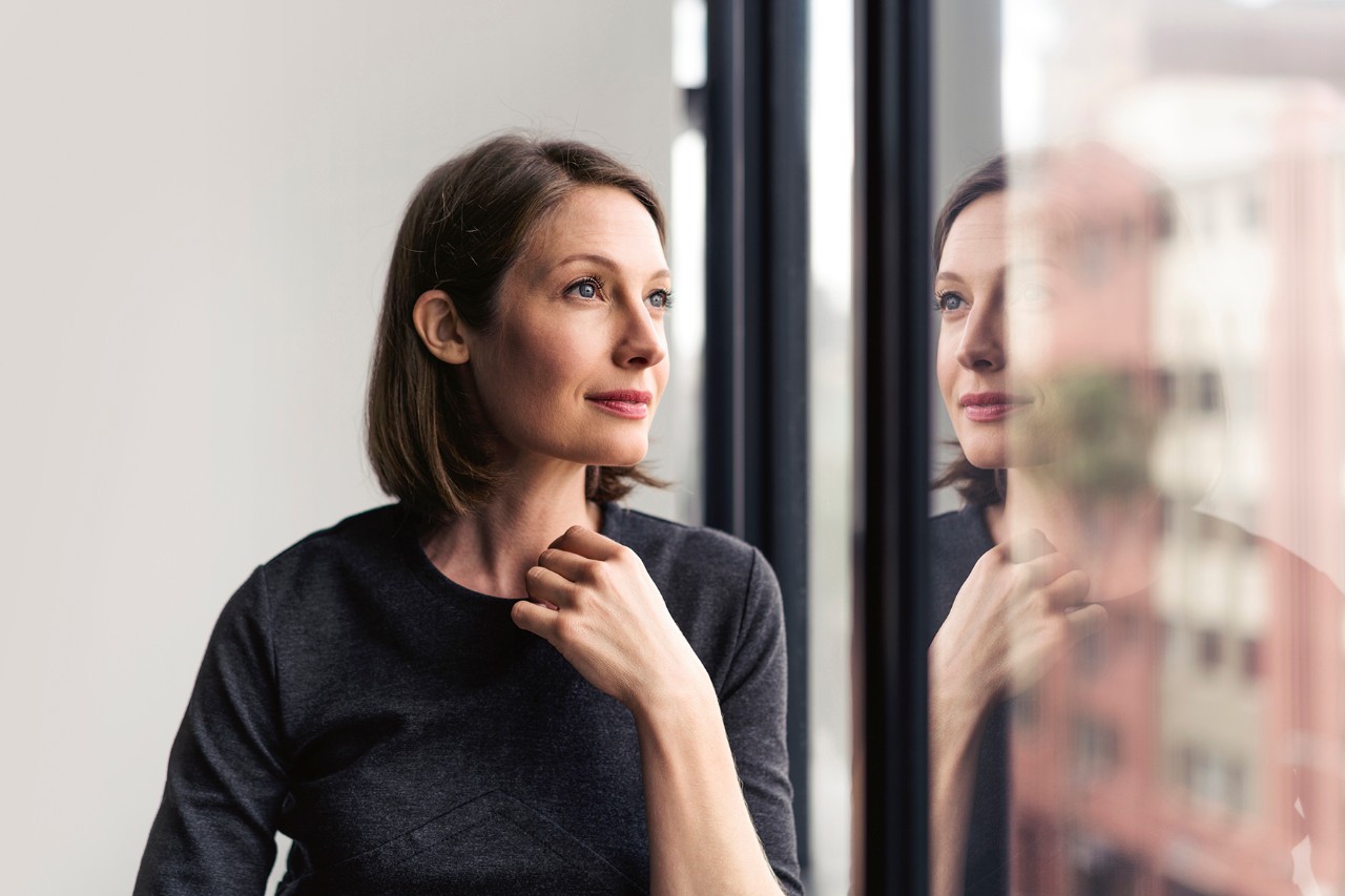 Thoughtful businesswoman looking through window in office.