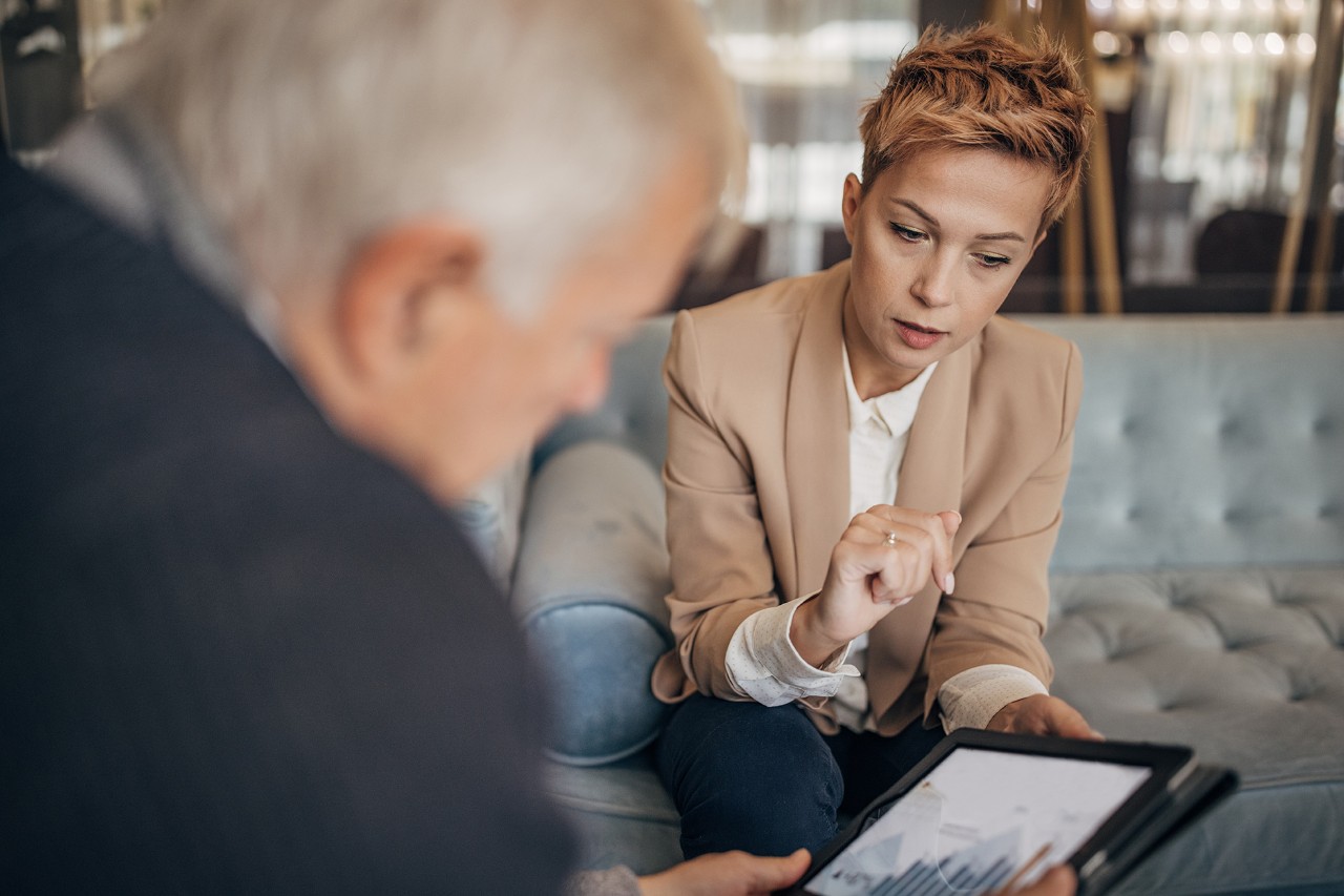 Woman showing an information oh her tablet to an old man